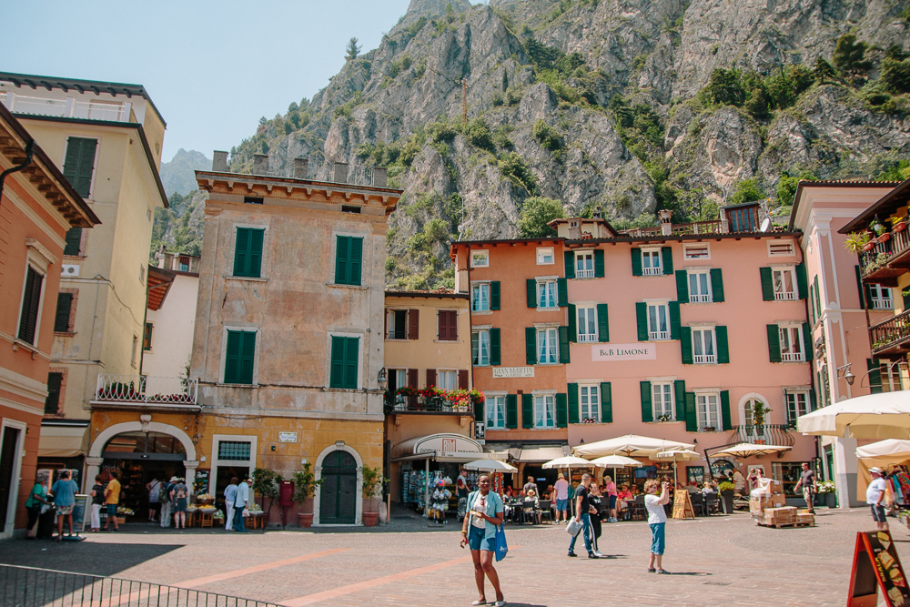 The Small Piazza in Limone, Lake Garda,, lined with colourful buildings infront of a large mountain